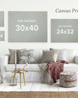 A botanical-style living room features an Offley Green set of 4 framed canvases (24x30) on the wall, a white sofa with patterned cushions, a renewable forest throw blanket, two side tables, and a decorative ottoman.