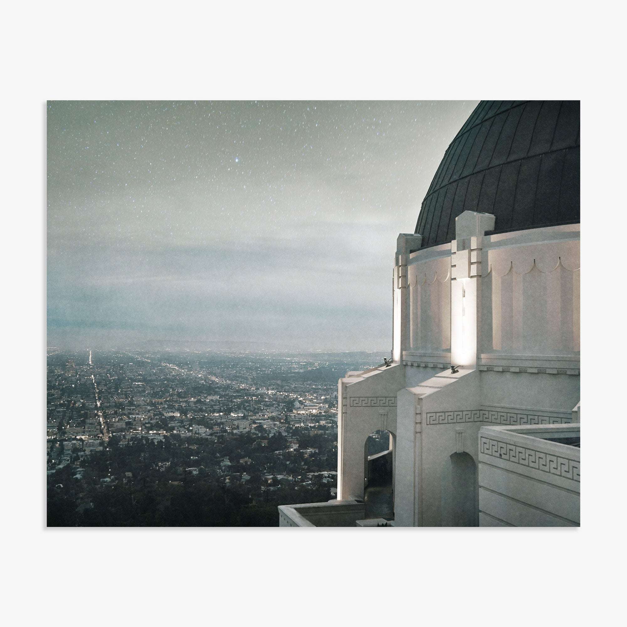 A nighttime view from the Offley Green Griffith Observatory Print, 'The Sky At Night' overlooking a sparkling Los Angeles cityscape under a starry sky, with the observatory's dome and ornate architecture in the foreground.