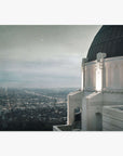 A nighttime view from the Offley Green Griffith Observatory Print, 'The Sky At Night' overlooking a sparkling Los Angeles cityscape under a starry sky, with the observatory's dome and ornate architecture in the foreground.