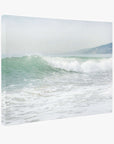 The Coastal Ocean Canvas Waves Wall Art, 'Breaking Surf' by Offley Green depicts a serene ocean wave gently crashing near the shore under coastal sunshine. Distant hills on the right add depth, creating a calm and peaceful scene perfect for relaxation. This beach-themed wall art is crafted on premium artist-grade canvas for lasting quality.