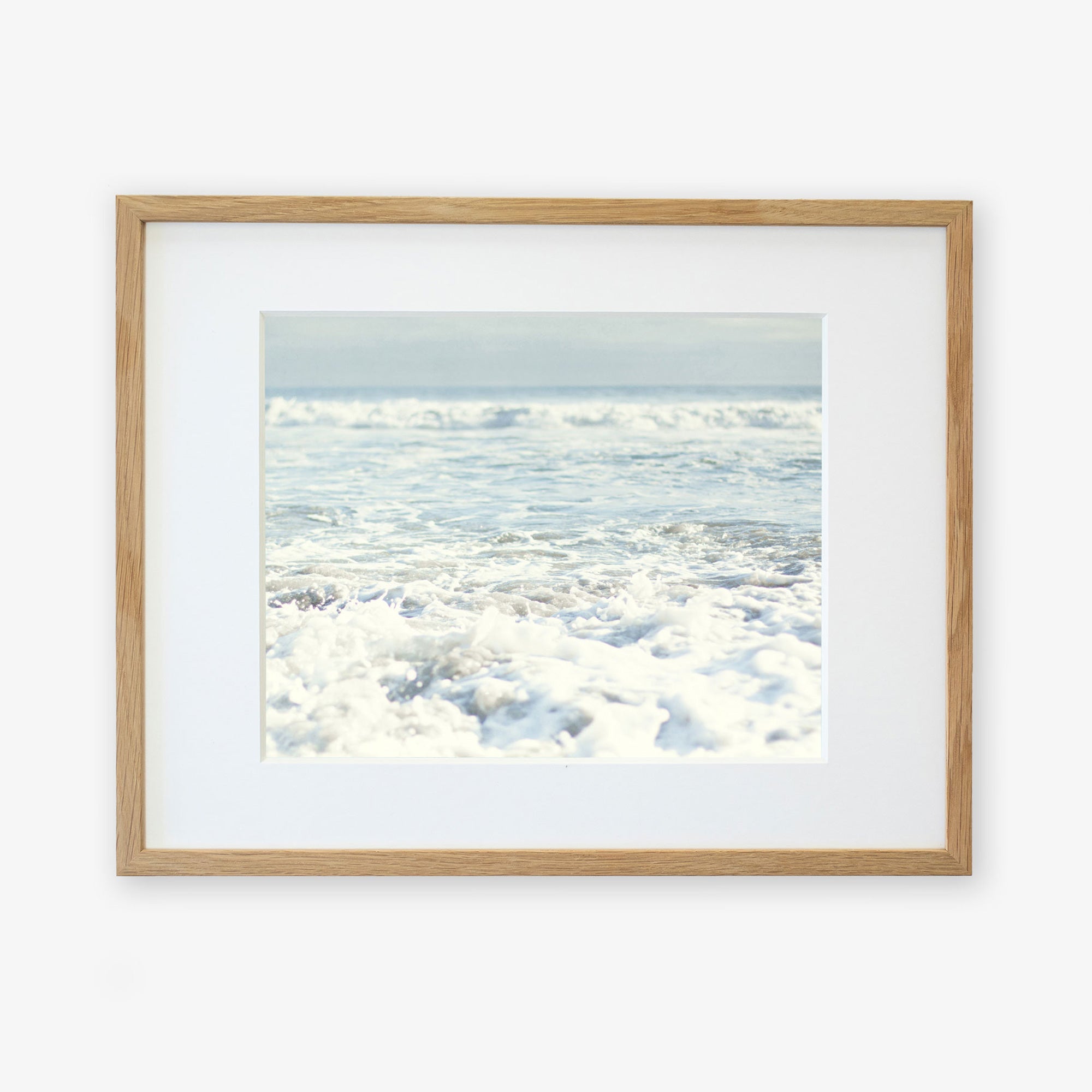 Framed photograph of a serene ocean scene at Pfeiffer Beach with gentle waves rolling in towards the shore. The image, printed on archival photographic paper, has soft, light colors, giving it a calming and peaceful atmosphere. The frame is made of light-colored wood and the mat board is white.
Introducing the Ocean Waves Print, 'Fresh Surf' by Offley Green.