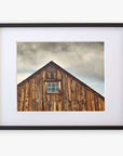 A framed photograph of an Offley Green Farmhouse Rustic Print, 'Old Barn at Bodie', centered and mounted on archival photographic paper, on a white gallery wall. The barn has weathered planks and a single window.