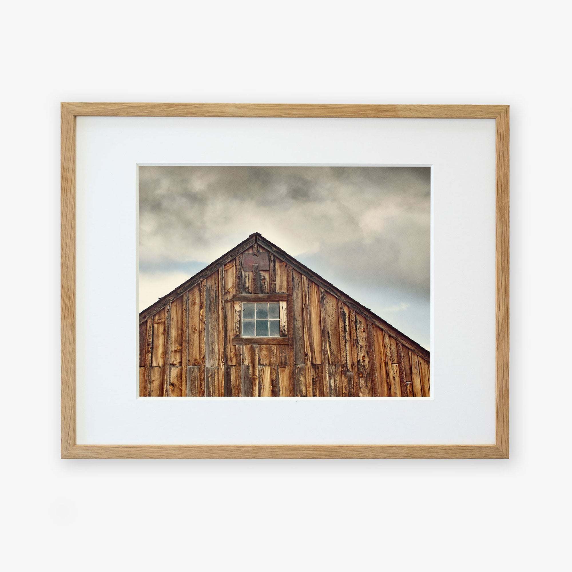 Offley Green&#39;s &#39;Old Barn at Bodie&#39; Farmhouse Rustic Print, emphasizing rustic textures and a single central window, is framed in a simple and light-colored frame printed on archival photographic paper.
