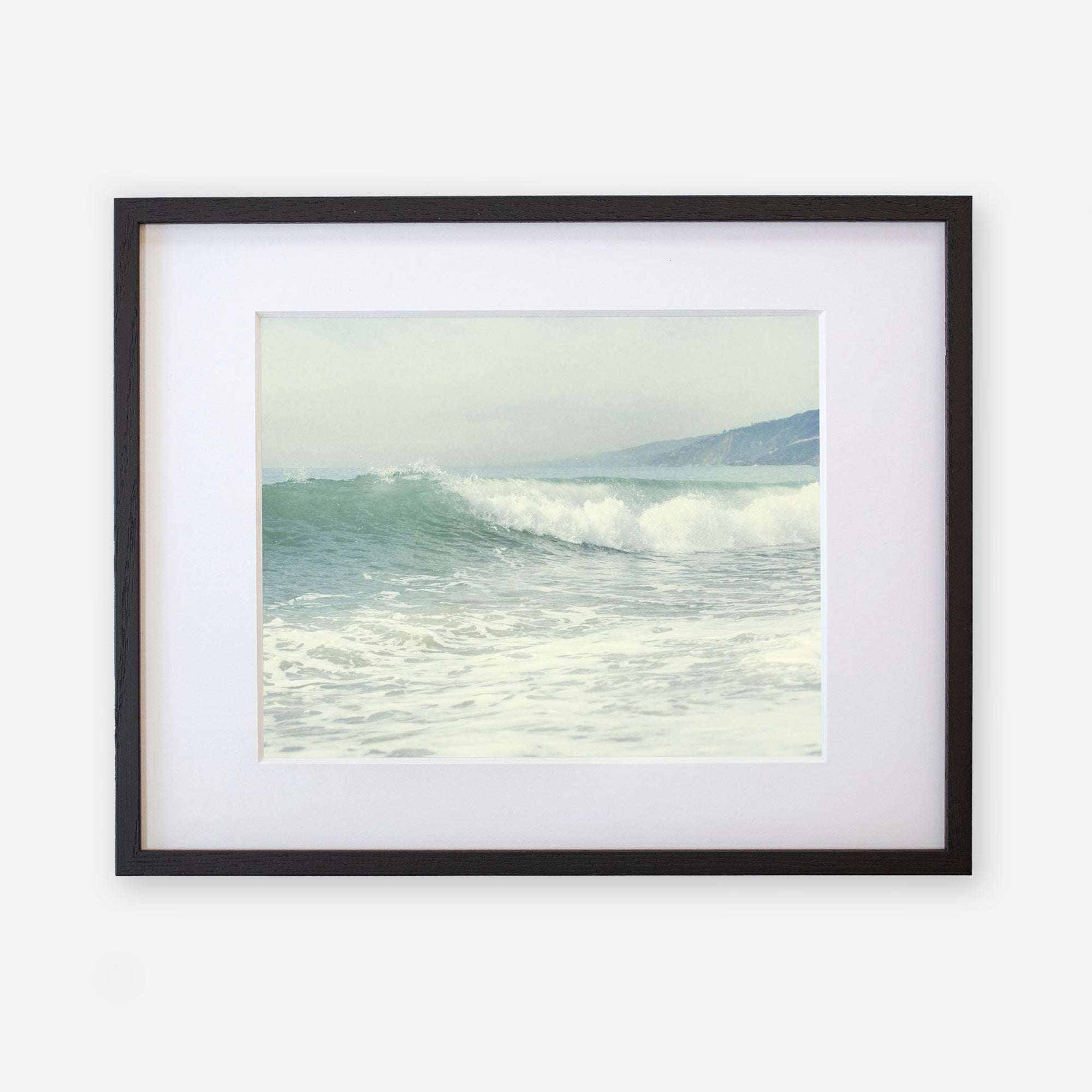 Coastal print of a breaking wave 'Breaking Surf' from Offley Green, framed in black with a white mat, capturing a serene oceanic scene.