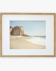 Offley Green's California Malibu Print, 'Point Dume' depicts a serene beachscape featuring a sandy beach with gentle waves at Point Dume, flanked by a large, rugged cliff under a clear sky.