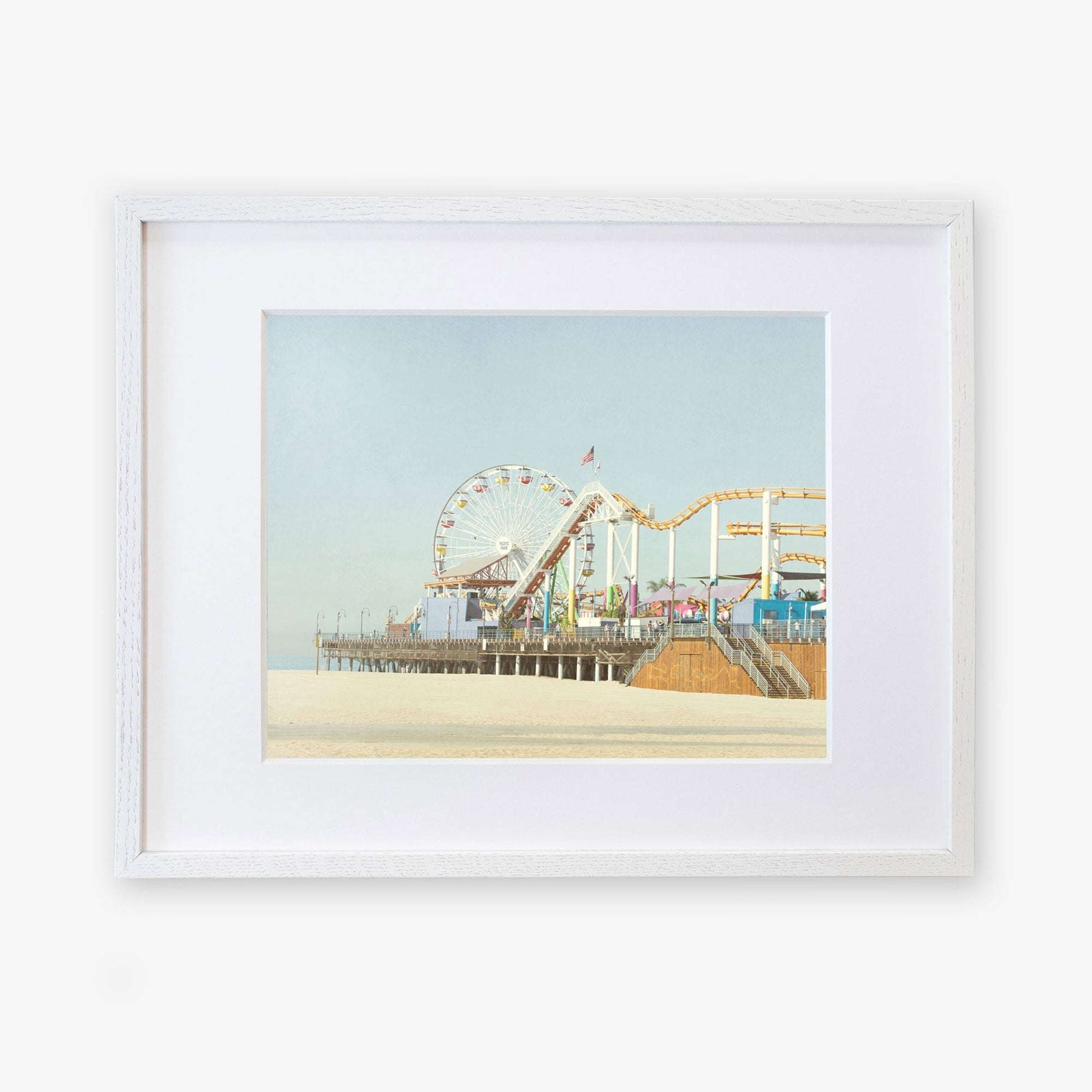 A framed illustration of Santa Monica Pier, featuring a ferris wheel and roller coaster, displayed against a calm blue sky. Get your Offley Green California Print, 'Santa Monica Pier' today!