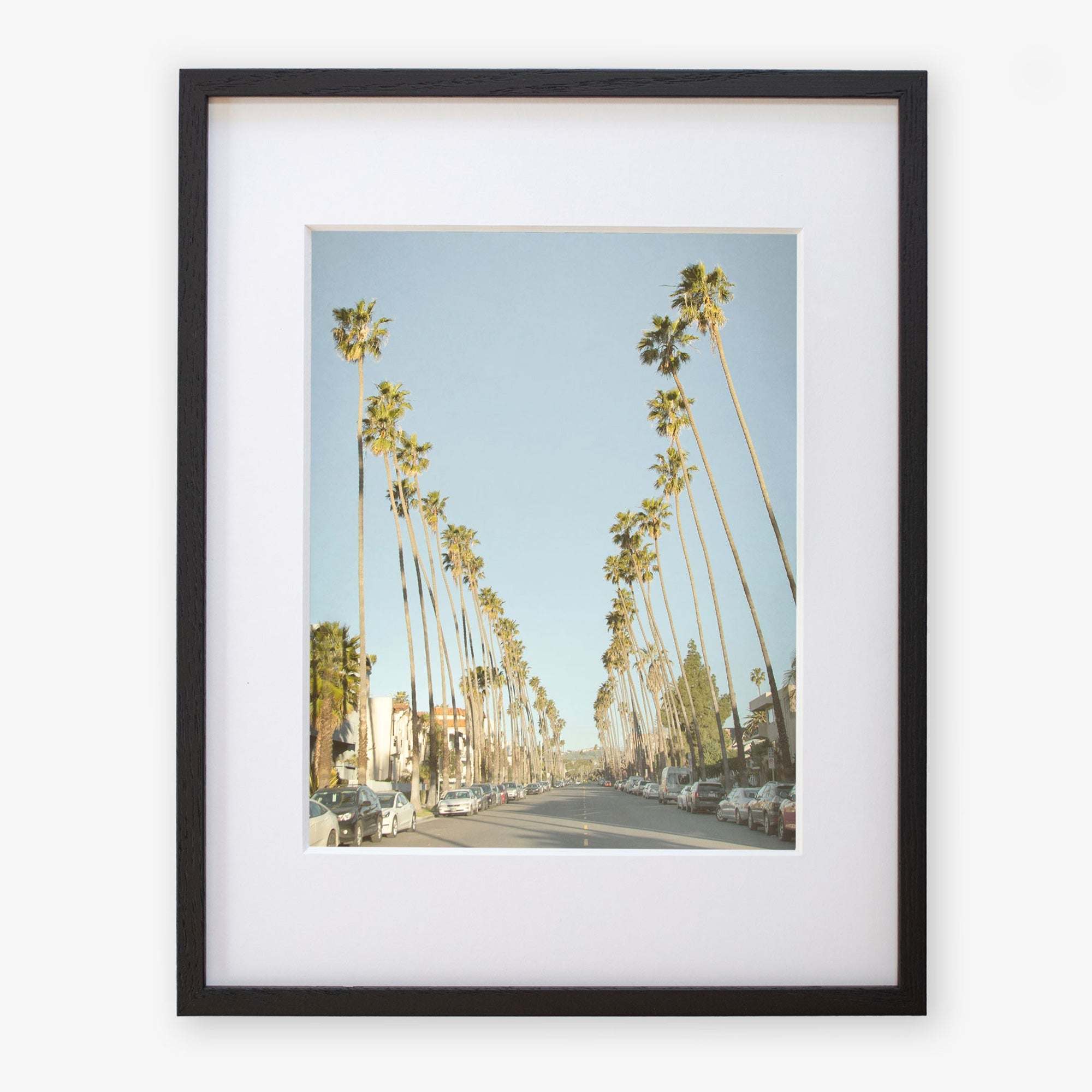 An art print of Los Angeles Palm Tree Lined Street 'Sunset Boulevard Dreams' in a black frame by Offley Green.