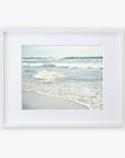 A framed photograph of Carlsbad State Beach with gentle waves and soft sand, displayed against a white background. The frame is simple and white, enhancing the tranquil Coastal Beach Print in California 'Surf and Sun' by Offley Green.