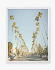 A framed photograph of Los Angeles Palm Tree Lined Street 'Sunset Boulevard Dreams' by Offley Green, lined with tall palm trees on both sides, parked cars, and a clear blue sky.