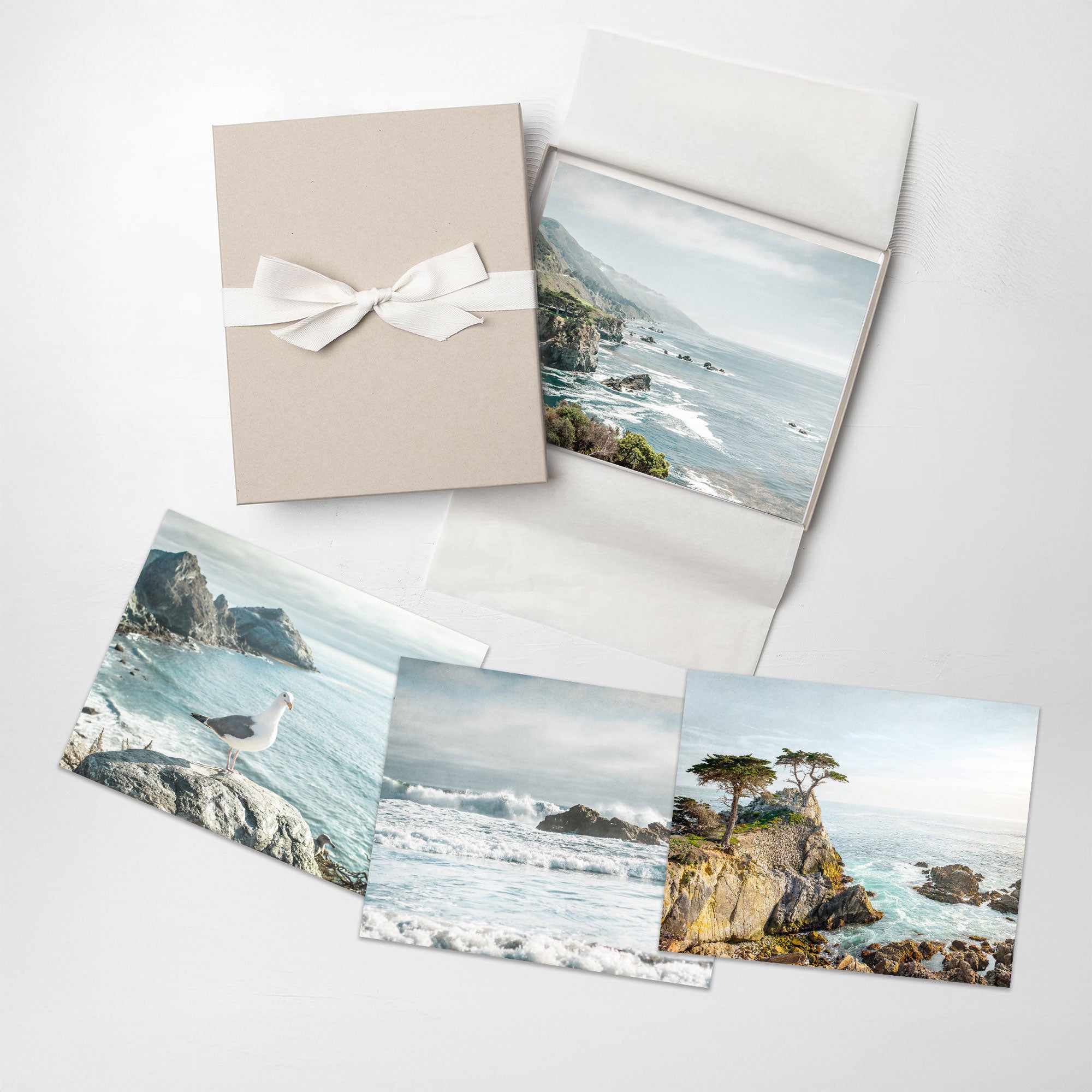 Set of 4 prints with coastal scenery and a gift box on a white background