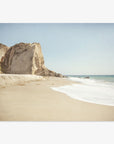 A serene Offley Green California Malibu Print, 'Point Dume' beach scene with soft waves lapping at the shore, a large cliff to the left, and a clear blue sky. The setting conveys a peaceful, natural coastal landscape.