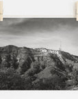 Black and white film noir photograph of the Offley Green Hollywood Sign Black and White Vintage Print, 'Old Hollywood' pinned up, set against a backdrop of a leafy hill with broadcasting antennas. The image has a rustic and vintage feel.