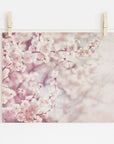 A photo of the Pink Floral Print, 'Dreamy Blossom' from Offley Green, clipped to a string with wooden clothespins, displayed against a white wall. The blossoms are in soft focus with a shabby pink and white color palette.