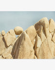 A series of large, smooth beige rocks in Joshua Tree National Park under a clear blue sky, closely packed and showing varying shapes and textures, resembling a rugged mountain landscape. The Offley Green 'Rock Formations' Joshua Tree Print captures the stunning beauty of this iconic park.