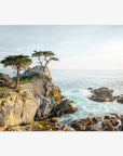 A serene coastal scene with rugged cliffs and a few trees overlooking the sparkling blue ocean under a clear sky. Light filters softly, creating a dreamy and tranquil atmosphere, perfect for Offley Green's California Coastal Print, 'Lone Cypress' photography.