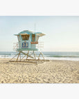 A picturesque scene of a lifeguard station, number 38, on a sandy beach with the ocean in the background under a clear sky, captured on Offley Green's California Coastal Print, 'Carlsbad Lifeguard Tower.'