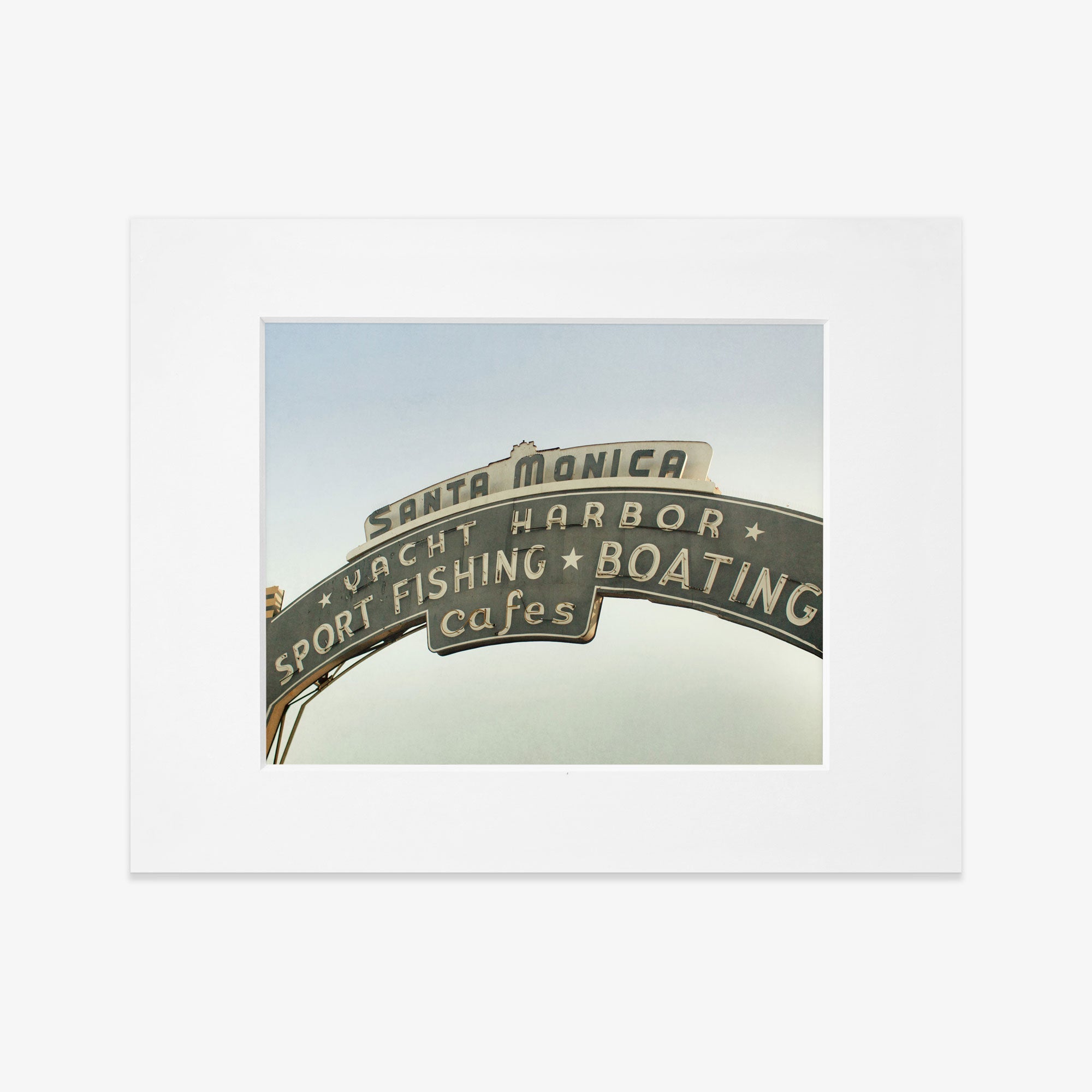 Offley Green&#39;s Los Angeles California Print, &#39;Santa Monica Pier Blues&#39; featuring the Santa Monica Pier sign with words &quot;sport fishing boating cafes&quot; against a cloudy sky, displayed in a white frame.