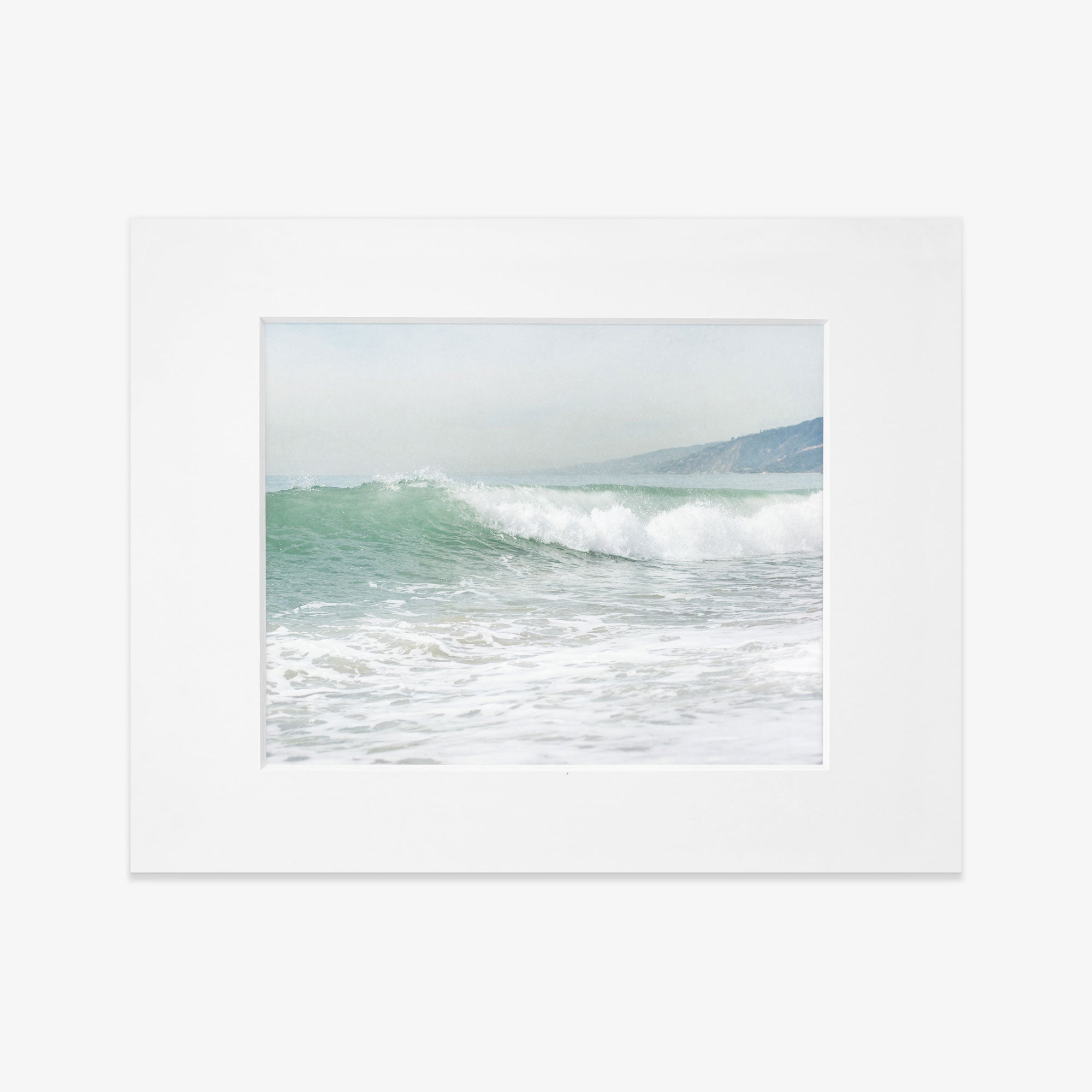 A framed photograph of a vibrant ocean wave cresting at a Southern California beach, with soft mist hovering above the water, set against a blurred coastal backdrop - Coastal Print of a Breaking Wave &#39;Breaking Surf&#39; by Offley Green.