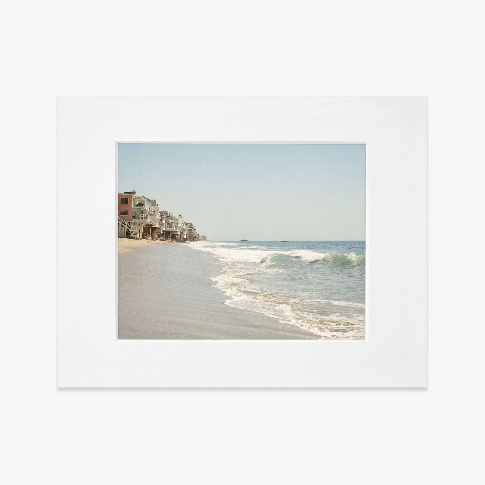 Polaroid photo showing a serene beach scene with gentle waves, a sandy shore, and a row of houses extending along the Malibu coastline under a clear sky. - Offley Green&#39;s Malibu Beach House Print, &#39;Ocean View&#39;