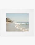 Polaroid photo showing a serene beach scene with gentle waves, a sandy shore, and a row of houses extending along the Malibu coastline under a clear sky. - Offley Green's Malibu Beach House Print, 'Ocean View'