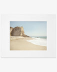 A Offley Green California Malibu Print, 'Point Dume' of Point Dume beach with a large rock formation on the left, gentle waves, and a clear sky, placed on a white background.