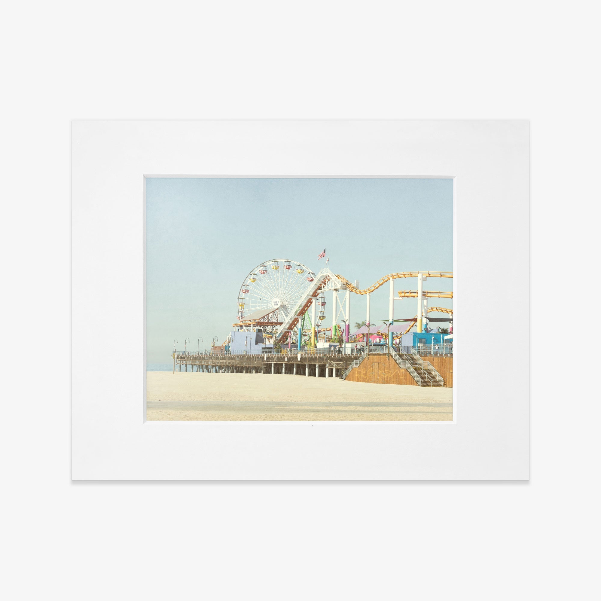 A framed California Print, &#39;Santa Monica Pier&#39; by Offley Green, depicting a vibrant seaside amusement park with a ferris wheel and roller coaster at Santa Monica Pier, displayed against a clear sky.