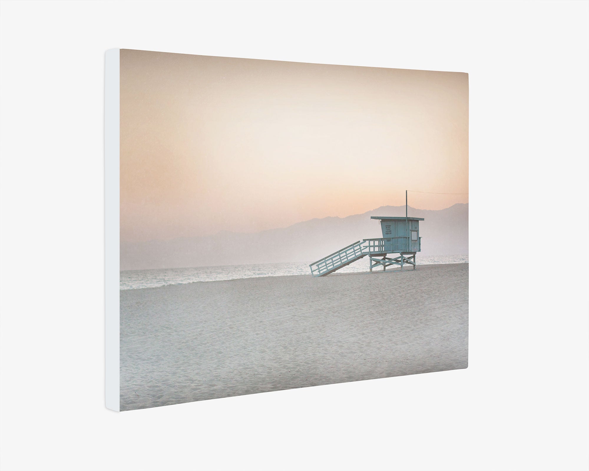 A Pink Coastal Wall Art featuring a serene beach scene at dusk with a &#39;Lifeguard Tower&#39;, soft pink hues in the sky, and distant mountains at Venice Santa Monica beach by Offley Green.