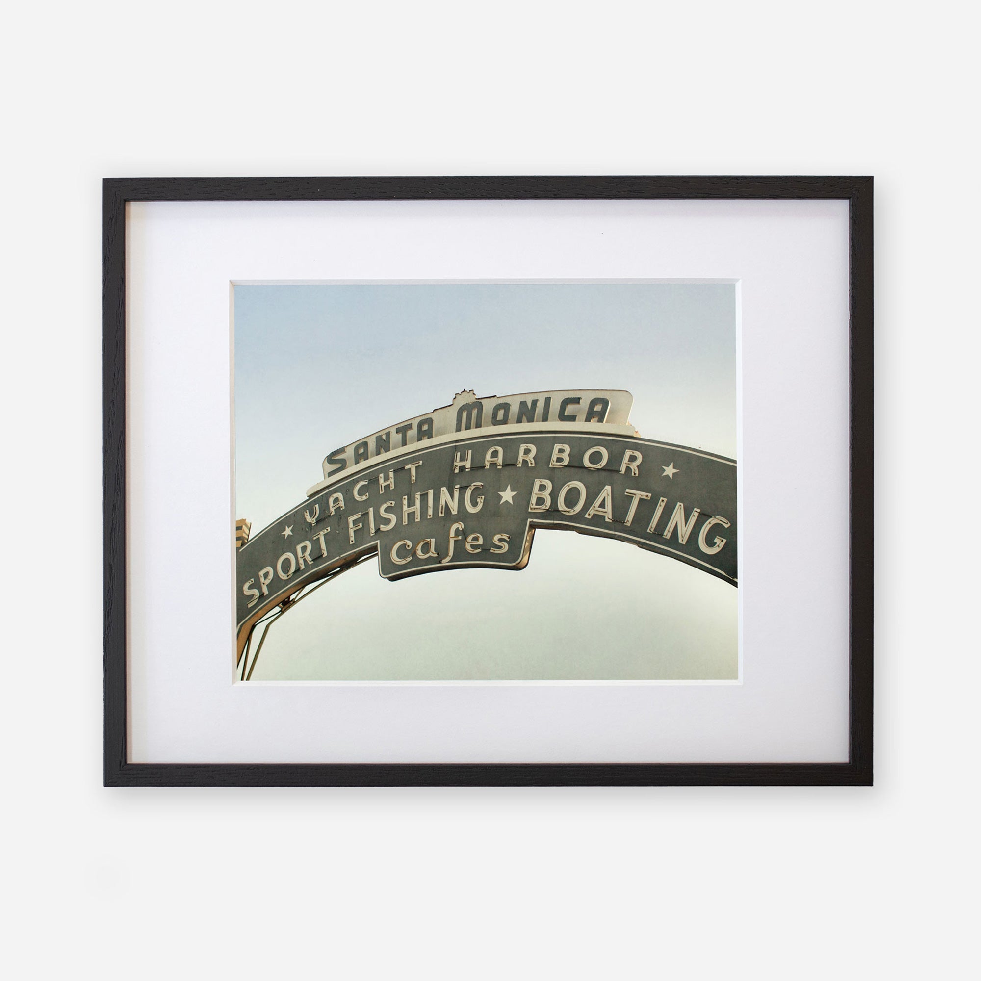 A framed archival Los Angeles California Print, &#39;Santa Monica Pier Blues&#39; by Offley Green, featuring the iconic Santa Monica Pier sign with words like &quot;sport fishing,&quot; &quot;boating,&quot; and &quot;cafes&quot; against a clear sky background.