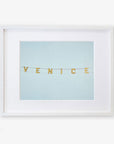 Unframed artwork featuring the Venice Beach Sign Print, 'Blue Venice' spelled out with string and small, square, gold letters against a light blue background, printed on archival photographic paper by Offley Green.