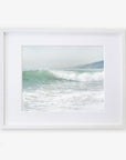 A framed Breaking Surf print of a vibrant ocean wave cresting at a Southern California beach, displayed in a simple white frame against a white background by Offley Green.