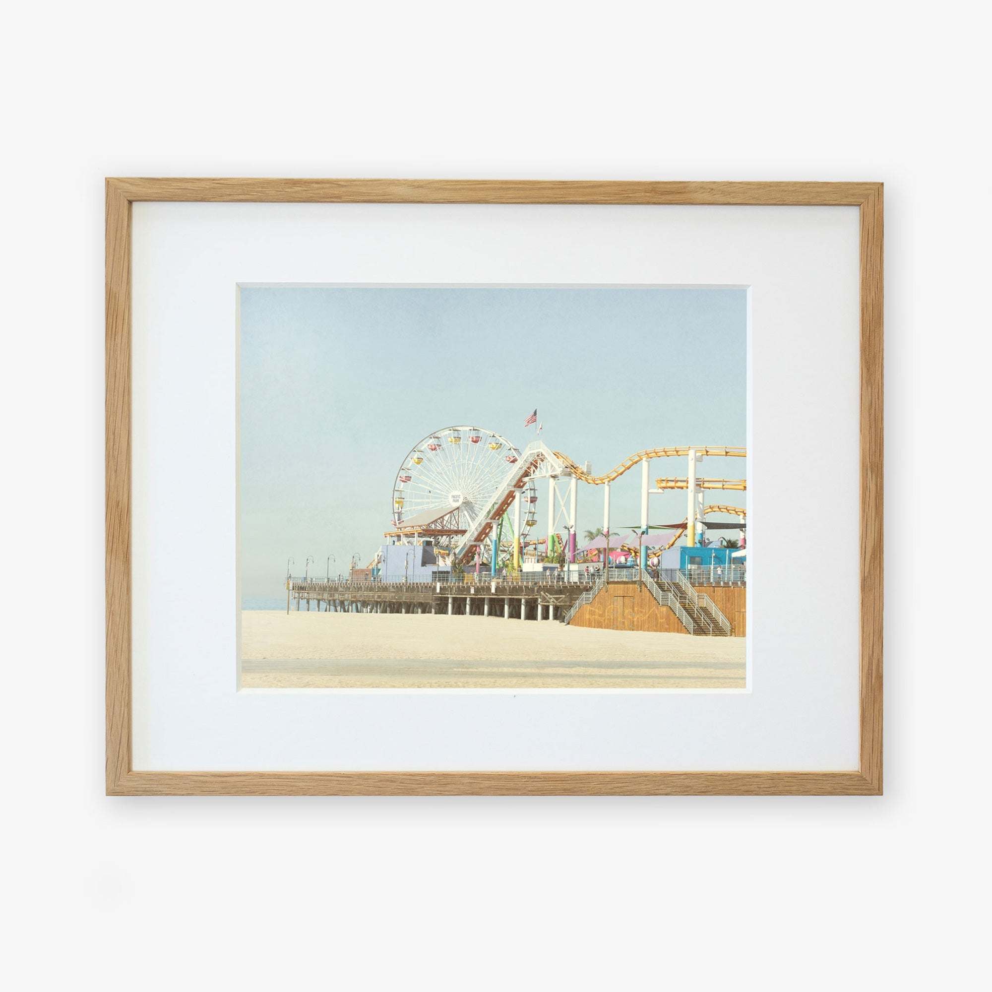 A framed illustration of a California Print, 'Santa Monica Pier' by Offley Green, with a ferris wheel and roller coaster over Santa Monica Pier, displayed against a plain background.