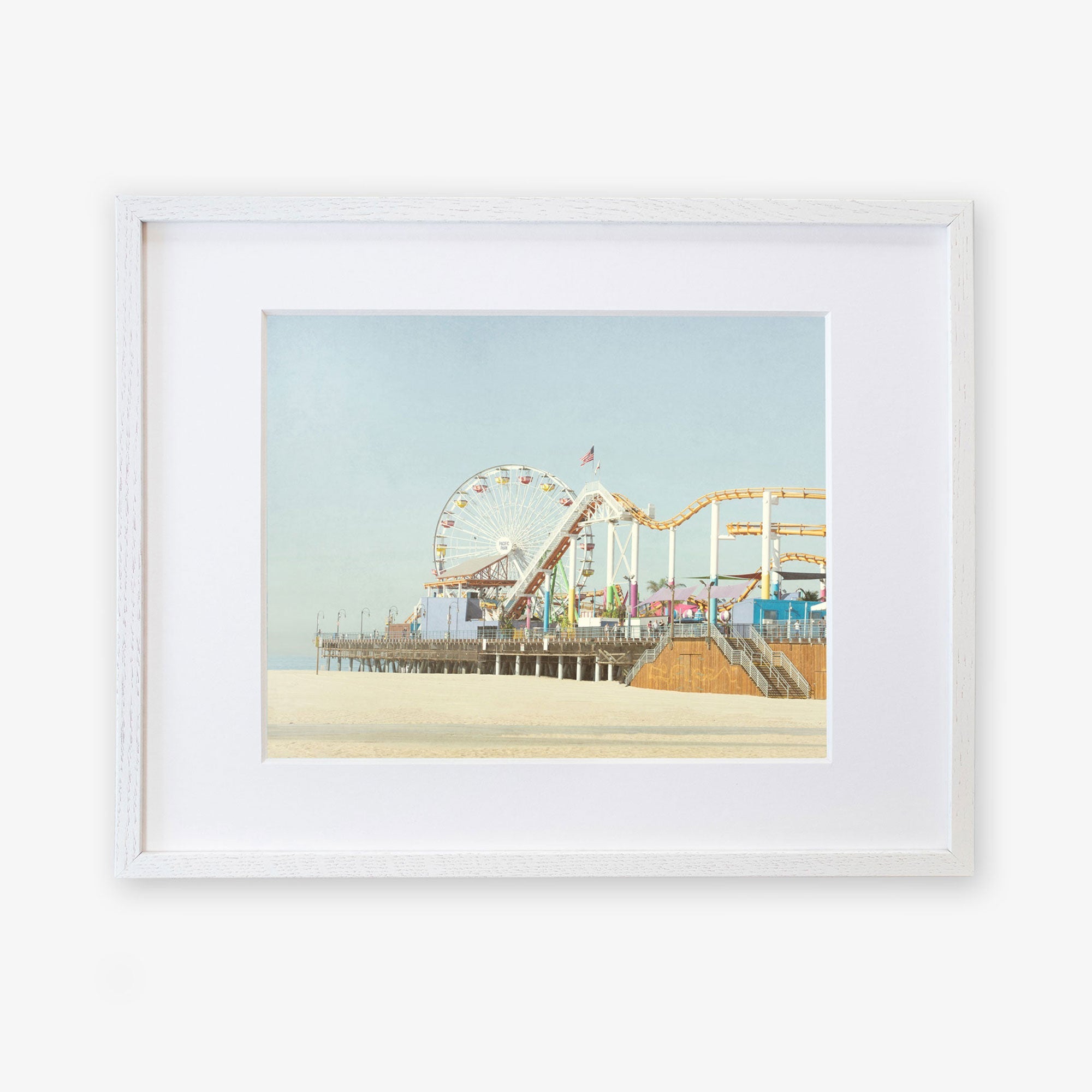 A framed illustration of Santa Monica Pier, featuring a ferris wheel and roller coaster, displayed against a calm blue sky. Get your Offley Green California Print, &#39;Santa Monica Pier&#39; today!