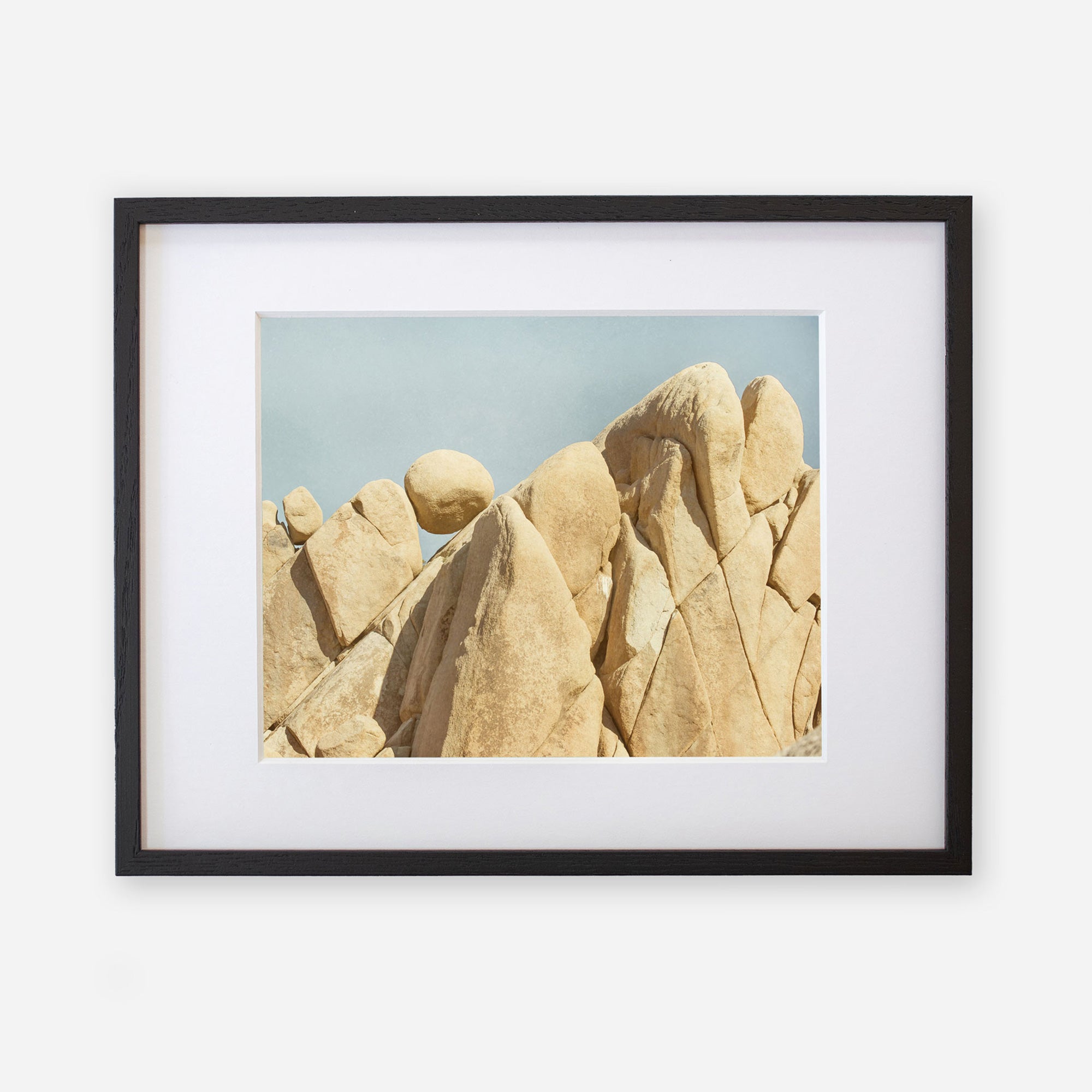 Unframed Joshua Tree print of &#39;Rock Formations&#39; featuring large, weathered sandstone rocks against a clear blue sky by Offley Green.