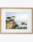 A framed California Coastal Print, 'Lone Cypress' by Offley Green, depicting a rugged coastline with several trees atop a cliff overlooking the ocean at Pebble Beach, displayed against a plain white background.