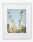 Framed photograph of Los Angeles Palm Tree Lined Street 'Sunset Boulevard Dreams' by Offley Green, cars parked along the road, and a clear blue sky.