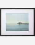A framed photograph of a tranquil ocean scene featuring Malibu Pier extending into the water under a soft, misty sky. The frame is black with a white mat border, enhancing the image’s calm mood.
Product Name: Offley Green Coastal Print of Malibu Pier in California 'All Calm in Malibu'