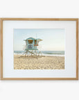 A framed photo of a lifeguard tower marked "38" standing on a sandy beach, printed on archival photographic paper, with serene ocean waves in the background under a clear sky - Offley Green's California Coastal Print, 'Carlsbad Lifeguard Tower'