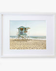 An unframed photograph of a lifeguard tower numbered 38 on a sandy beach, with the ocean in the background under a clear sky. The Offley Green 'California Coastal Print, Carlsbad Lifeguard Tower' exemplifies a serene beach setting.