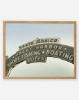 A framed archival photographic print of the iconic Santa Monica yacht harbor sign, featuring words like "sport fishing," "boating," and "cafes" on an arched metallic structure, against a plain Offley Green Los Angeles California Print, 'Santa Monica Pier Blues'