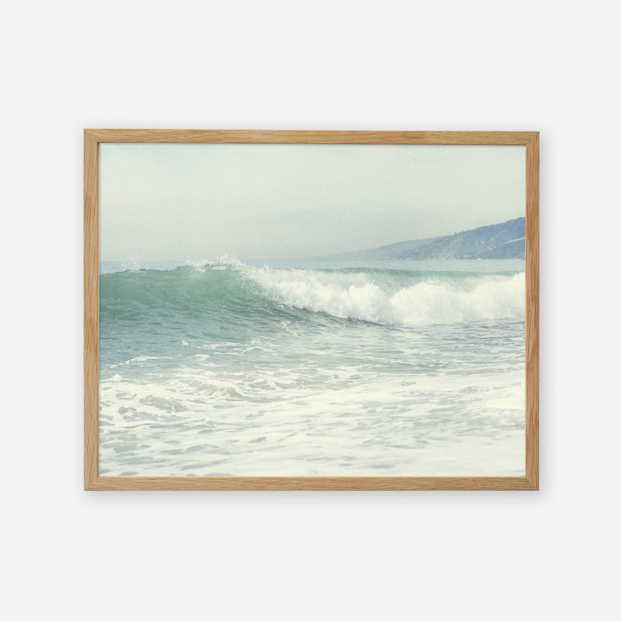 A framed painting of a calm Southern California beach scene with gentle waves and a hazy coastline in the background, giving a tranquil and serene vibe: Offley Green&#39;s Coastal Print of a Breaking Wave &#39;Breaking Surf&#39;