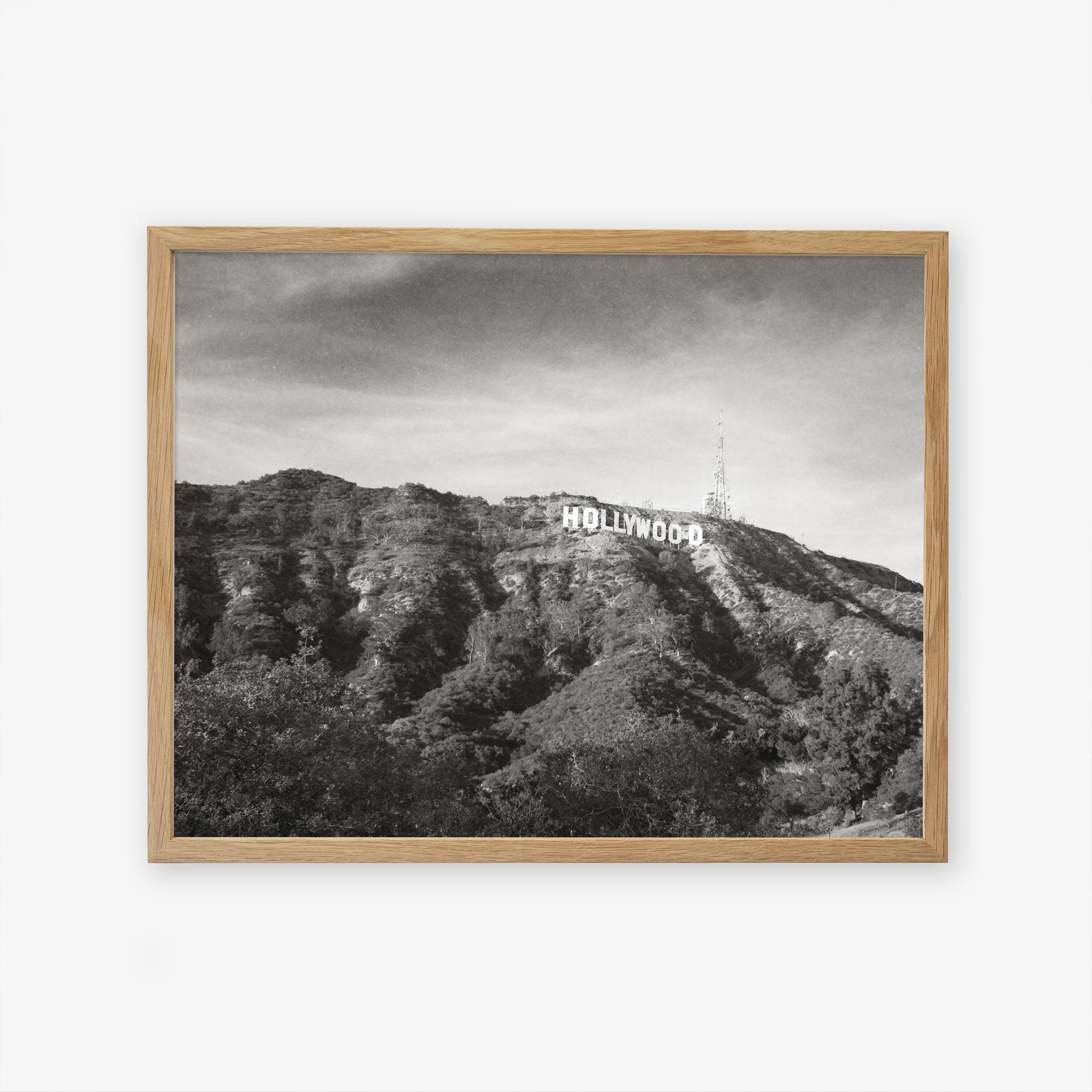 Black and white photo of the Offley Green Hollywood Sign Black and White Vintage Print, &#39;Old Hollywood&#39; on a hill, printed on archival photographic paper, framed in a wooden picture frame, with a clear sky in the background.
