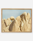 A framed photograph of a natural beige rock formation in Joshua Tree National Park, with jagged, smooth surfaces under a clear blue sky. The formation consists of clustered, vertical rock peaks. Offley Green's Joshua Tree Print, 'Rock Formations' showcases this stunning scene beautifully.