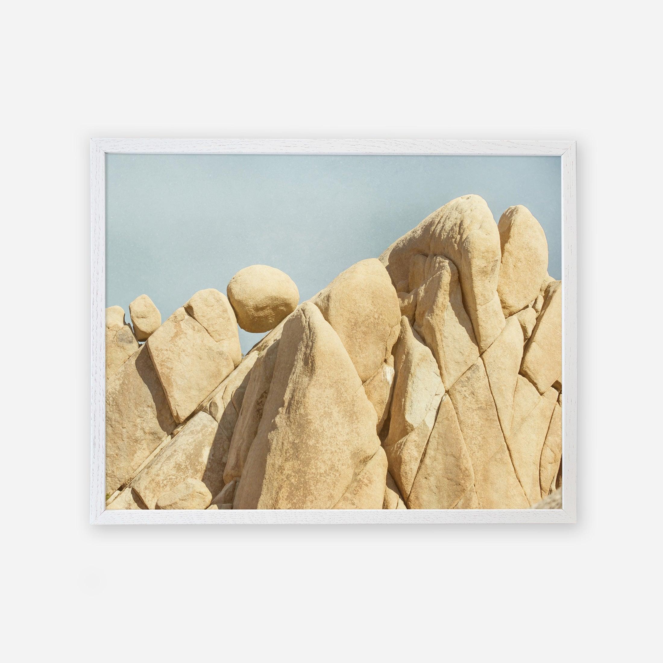 A framed photo of weathered, rounded rock formations in Joshua Tree National Park against a pale blue sky. The rock textures are smooth and intricate, highlighting natural erosion. The frame is simple and white.
Product: Offley Green&#39;s Joshua Tree Print, &#39;Rock Formations&#39;