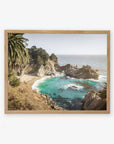 A framed scenic coastal landscape of Big Sur, showcasing a vibrant turquoise sea, rocky cliffs, and lush green trees under a clear blue sky. The product is the Offley Green Big Sur Coastal Print, 'Julia Pffeifer'.