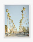 A framed photograph of Los Angeles Palm Tree Lined Street 'Sunset Boulevard Dreams' by Offley Green, lined with tall palm trees on both sides, parked cars, and a clear blue sky.