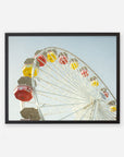 A framed photograph of the Offley Green Santa Monica Ferris Wheel Print, 'Ferris Above' with colorful yellow and red cabins against a clear blue sky, angled view looking up from the base.