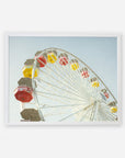 A colorful Santa Monica Ferris Wheel Print with red, yellow, and white cabins against a clear sky at Santa Monica Pier, framed as if it is a picture hanging on a wall.