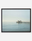 A framed photograph of a tranquil seascape featuring Malibu Pier with a small building extending into the calm ocean under a clear sky, Coastal Print of Malibu Pier in California 'All Calm in Malibu' by Offley Green.