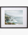Framed archival photographic print of a Big Sur landscape along California Highway 1, featuring rugged cliffs and a misty ocean view, with hints of green vegetation under a cloudy sky by Offley Green.