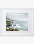 A framed photograph of a scenic Big Sur view, showing a rocky cliffside descending into a foggy ocean with sparse vegetation and an overcast sky - Offley Green's Big Sur Landscape Print, 'Rocky Rocks'